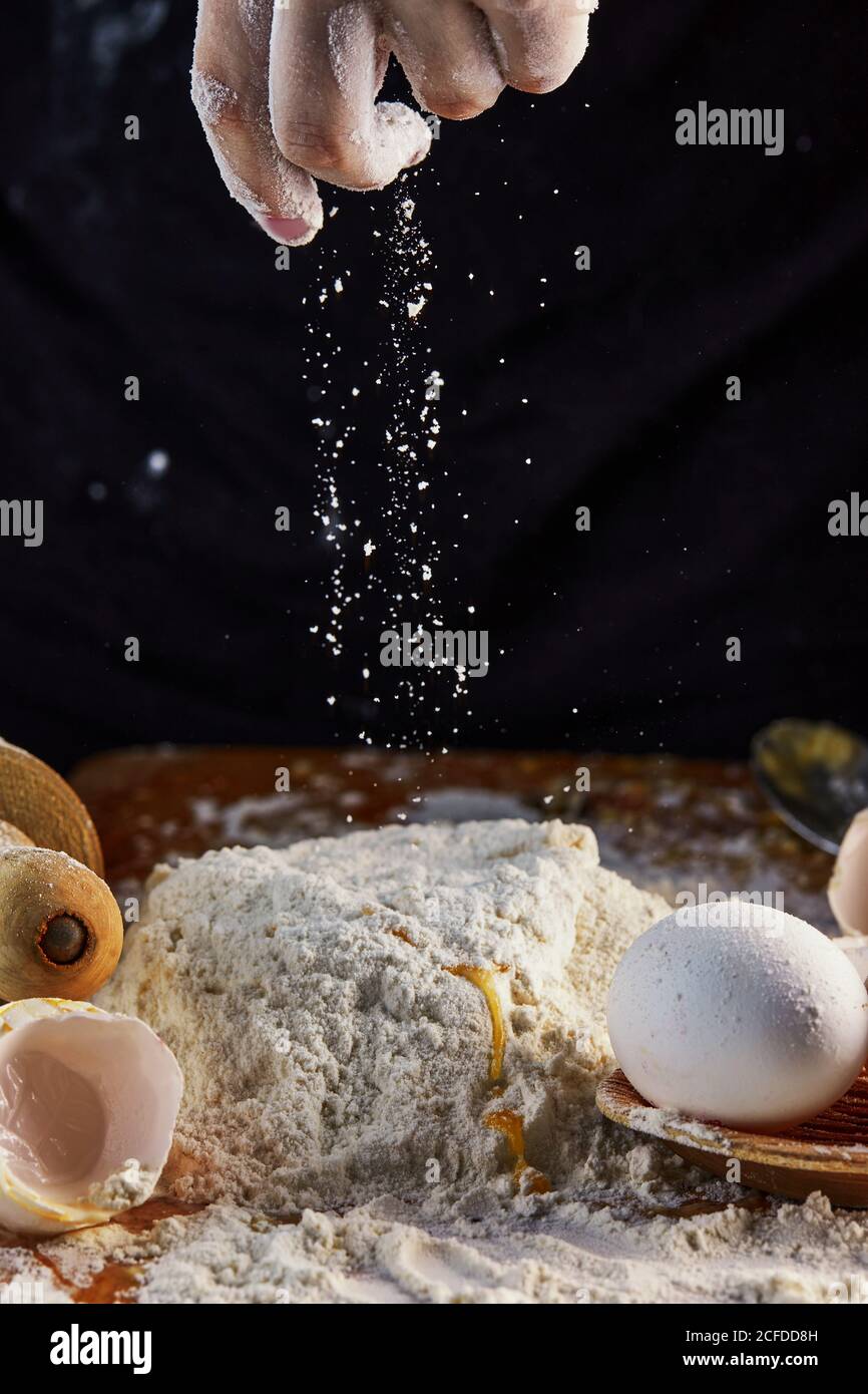 Female hands adding flour to dough, kneading dough for baking. Flour in ...