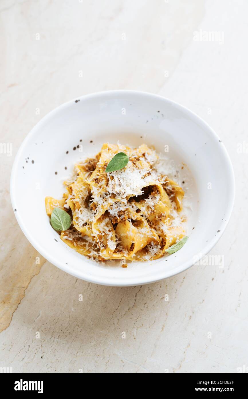 From above of tasty dish with wide pasta sprinkled with cheese and decorated with fresh mint in restaurant Stock Photo