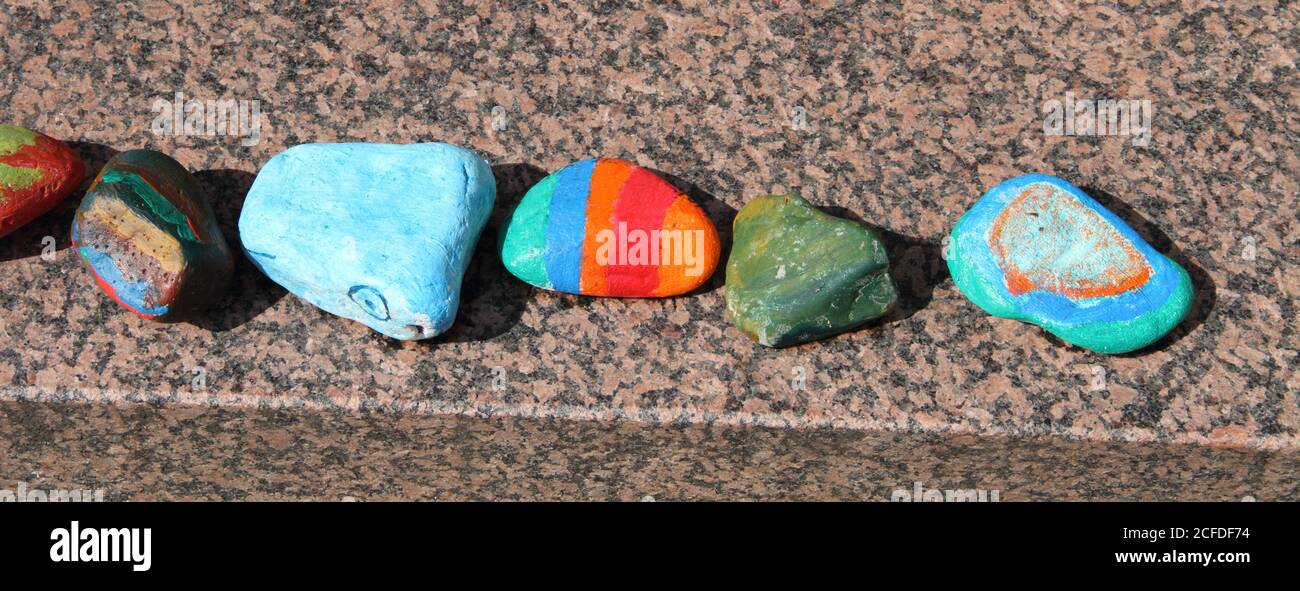 brightly painted pebbles on a brick wall Stock Photo