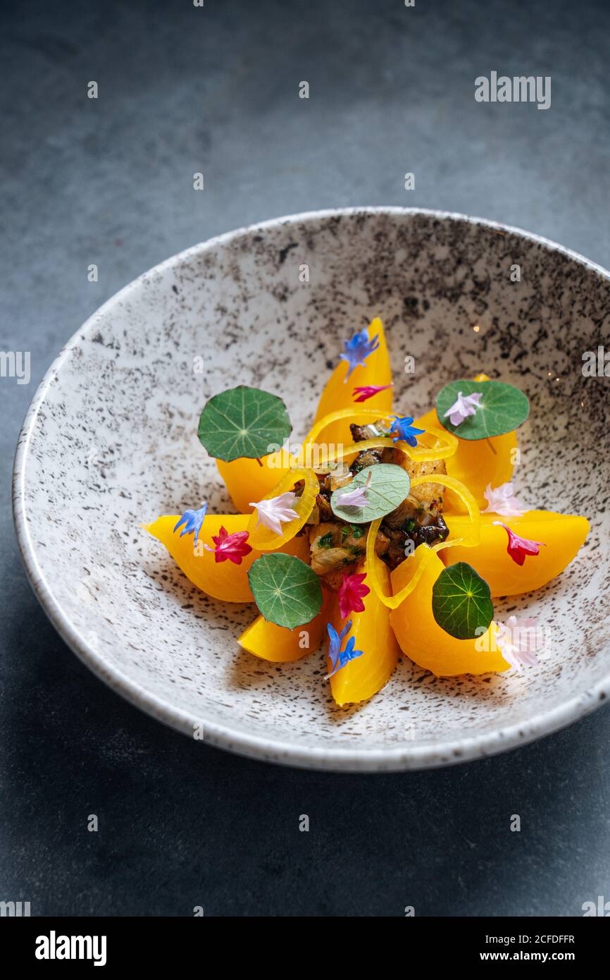 From above of sliced of orange fruit leading out in circle with fried white mushrooms in center on stylish plate Stock Photo