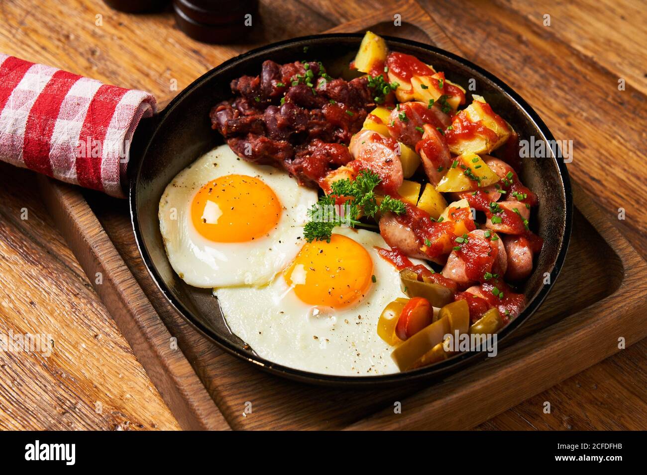 Fried eggs with vegetables in pan Stock Photo