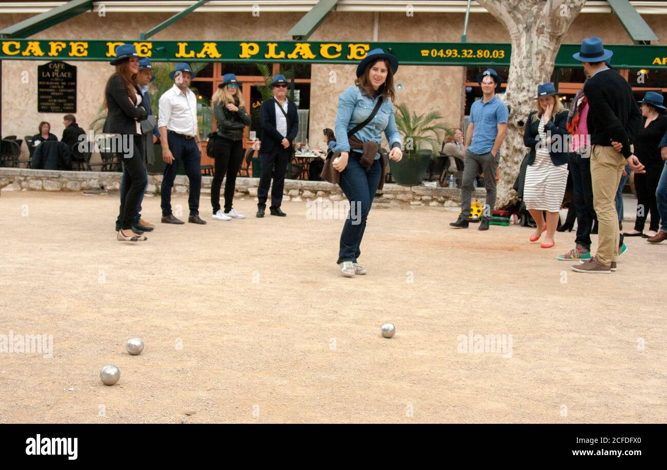 Saint-Paul-de-Vence France The petanque team after throwing the ball.  Every member of the team, young women and men, wears a blue hat. Stock Photo