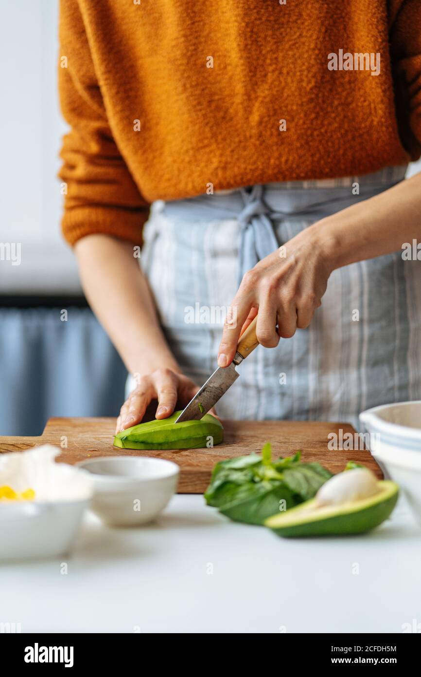 Woman cutting avocado on cutting board Stock Photo