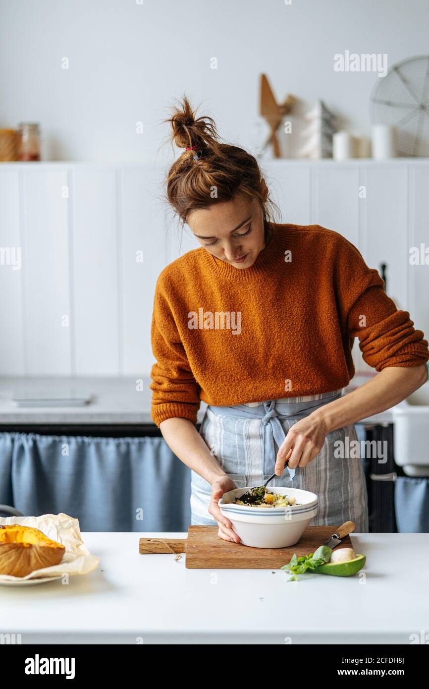 Woman adding raisins into bowl Stock Photo