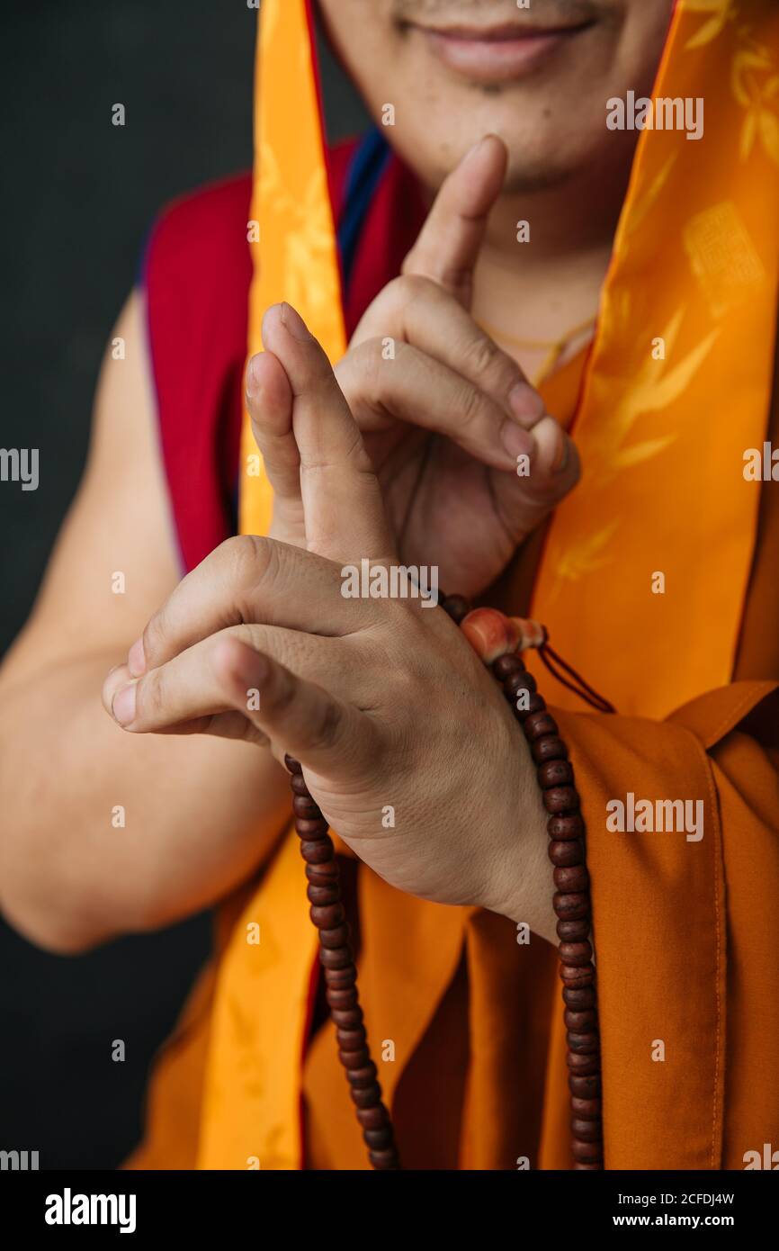 Crop Tibetan Woman in traditional clothes with prayer beads doing mudra gesture with hands Stock Photo
