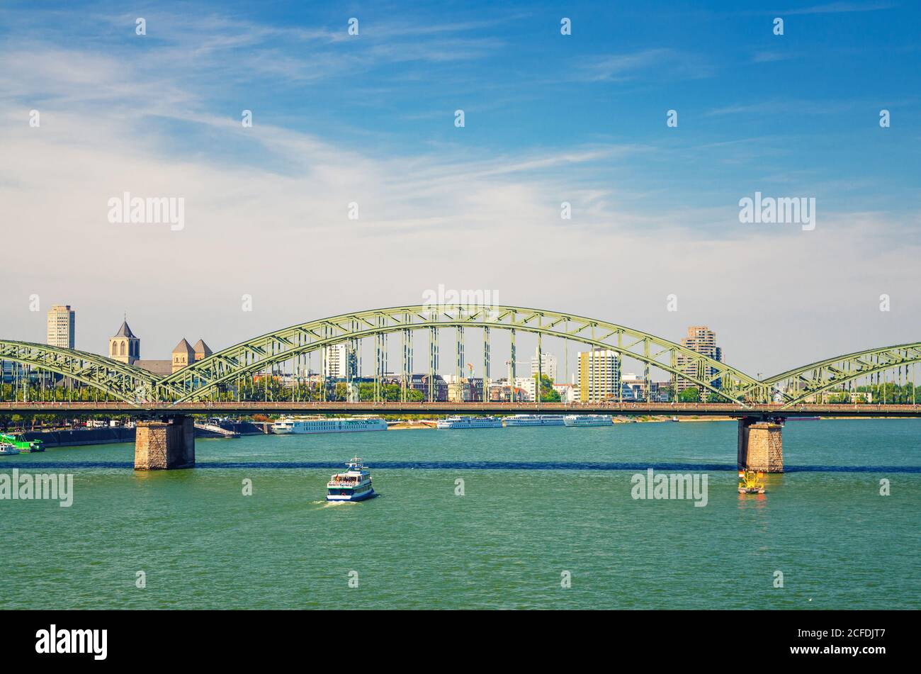 The Hohenzollern Bridge or Hohenzollernbrucke across Rhine river with tourist boat sailing on water, pedestrian and railway steel bridge, Cologne city centre, North Rhine-Westphalia, Germany Stock Photo