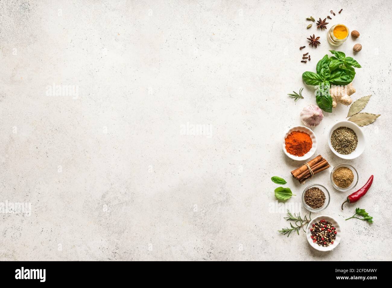 Various Spices, Herbs and Condiments on white stone table, top view