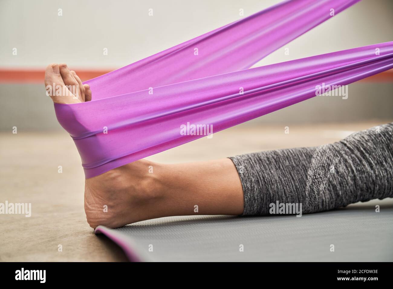 Side view of barefoot female in sport leggings stretching muscles with
