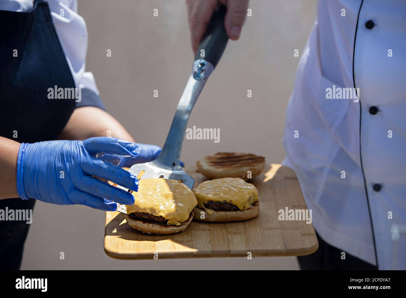 The hands of the cook make a hamburger. Fast food preparation process. Stock Photo