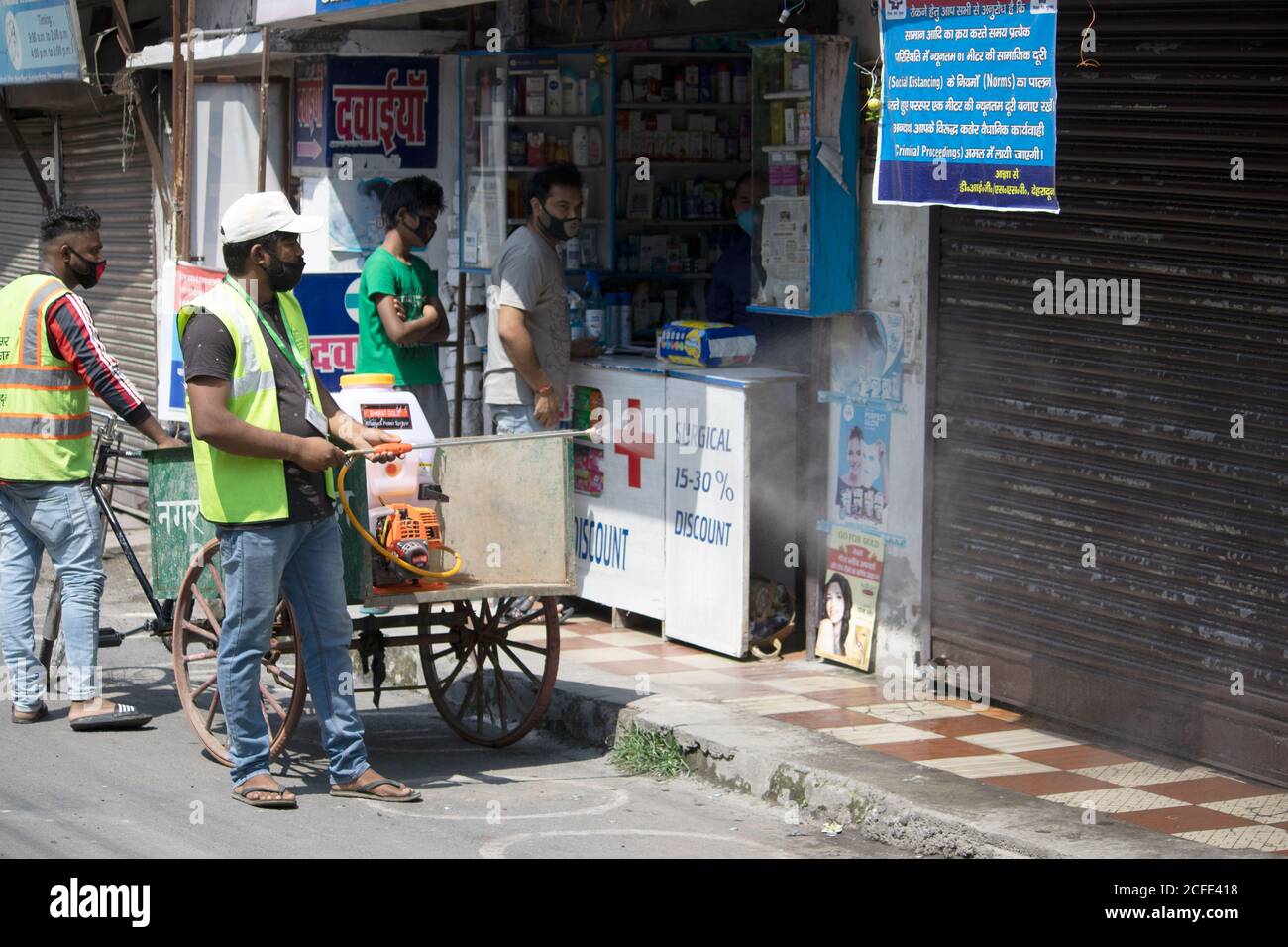 Municipal worker sanitizes a shop, wearing face mask. Stock Photo