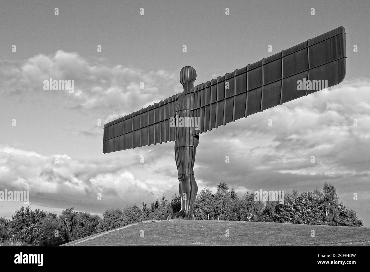 The landmark iconic Angel of the North statue in Gateshead, Tyne and Wear. Captured in golden light to contract the rust colour against cloudy blue sk Stock Photo