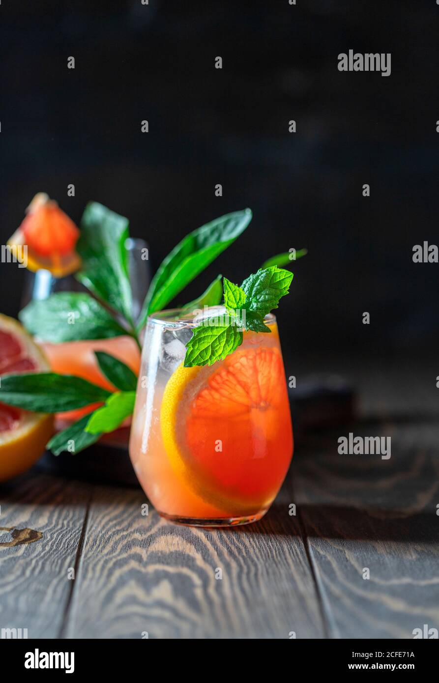 A glass of freshly squeezed grapefruit juice and mint on a dark wooden table. Refreshing summer cocktail. Stock Photo