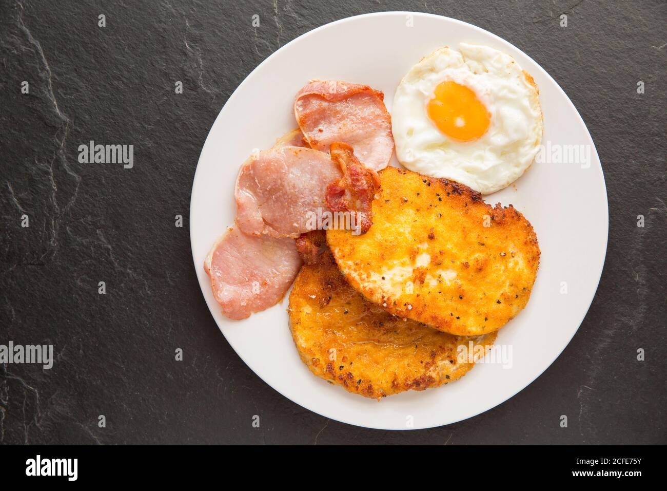 Two fried slices of a giant puffball, Calvata gigantea, that have been dipped in egg and breadcrumbs and served with bacon and eggs. Great care should Stock Photo