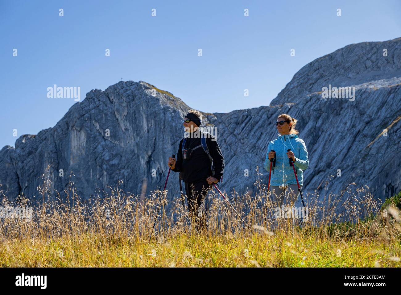 Man and woman hiking in Osterfelder at the foot of the Alpspitze look into the distance, in the background the Wetterstein Mountains with Stock Photo