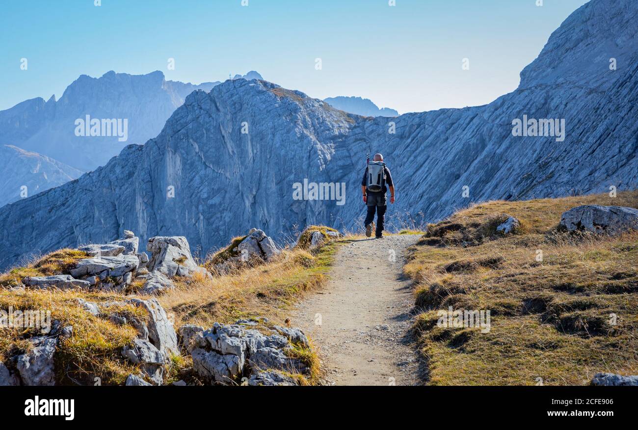 Man hiking at the foot of the Alpspitze with a view towards the Bernadeinkopf in the Wetterstein Mountains, blue sky, hiking trail, Stock Photo