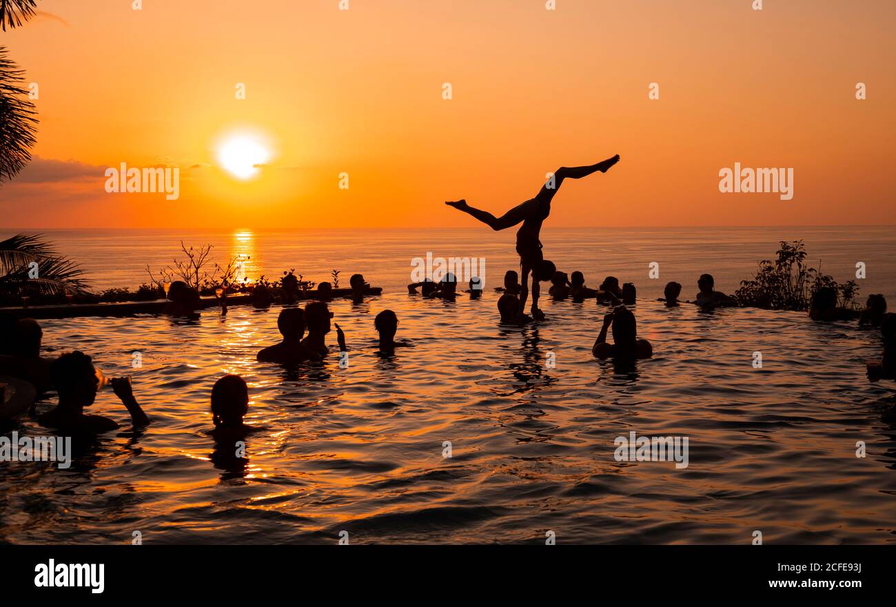Young woman, young women, young men, acrobatics, infinity pool, swimming pool, sunset, sun, pool party, silhouette, sea, Central America, Costa Rica Stock Photo