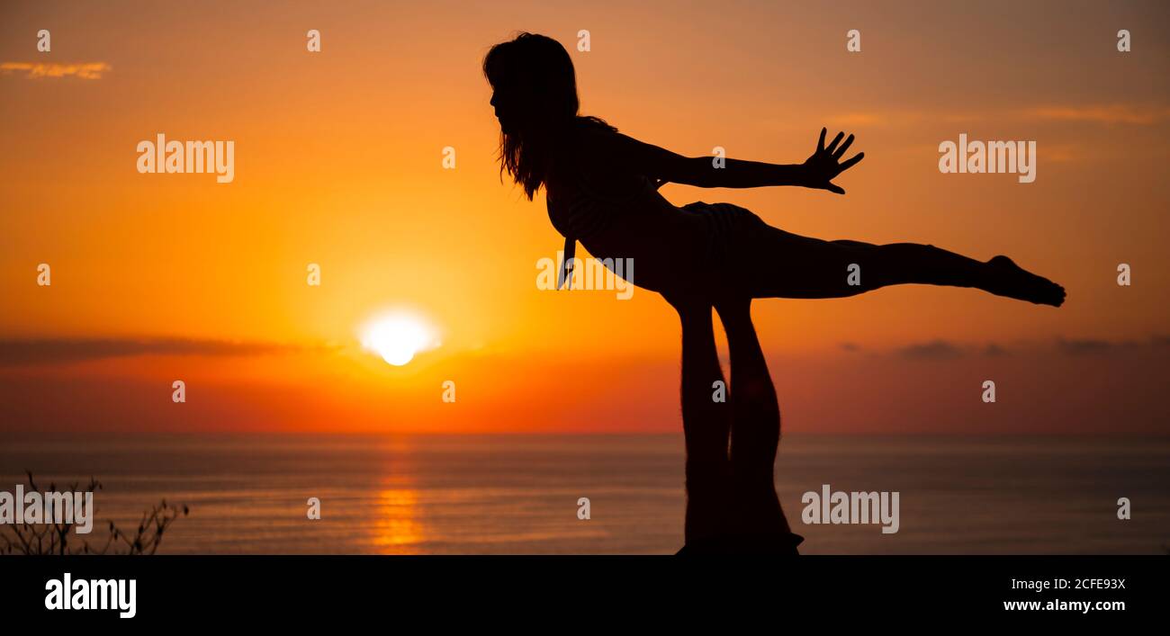 Young woman, acrobatics, sunset, sun, silhouette, sea Stock Photo