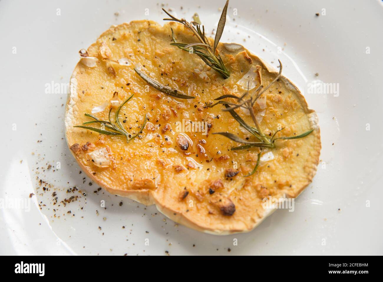 A slice of a giant puffball, Calvatia gigantea, that has been grilled with rosemary, minced garlic and olive oil and sprinkled with freshly ground bla Stock Photo