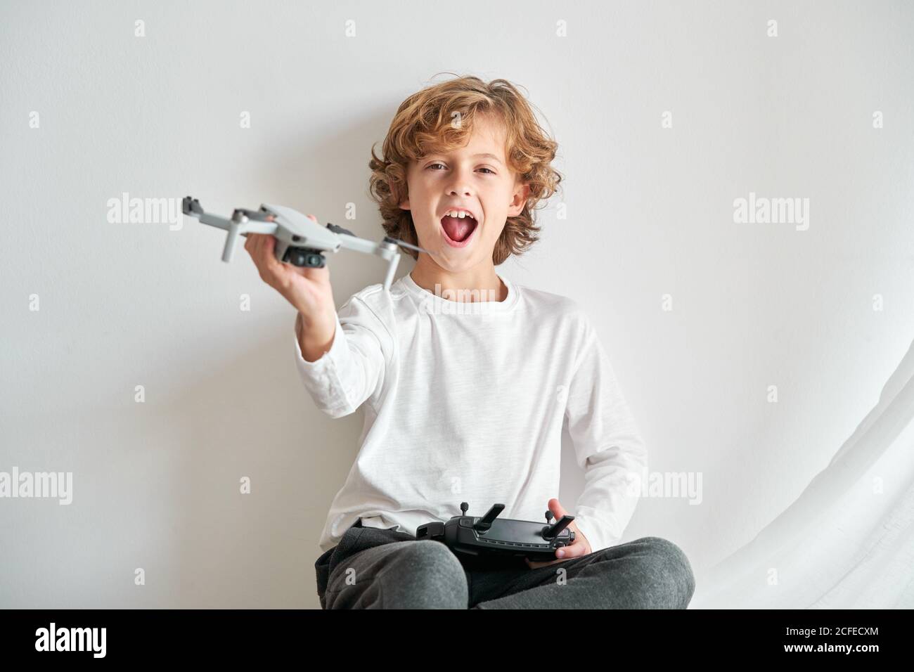 Child manipulating a drone and the remote control just given to him Stock Photo
