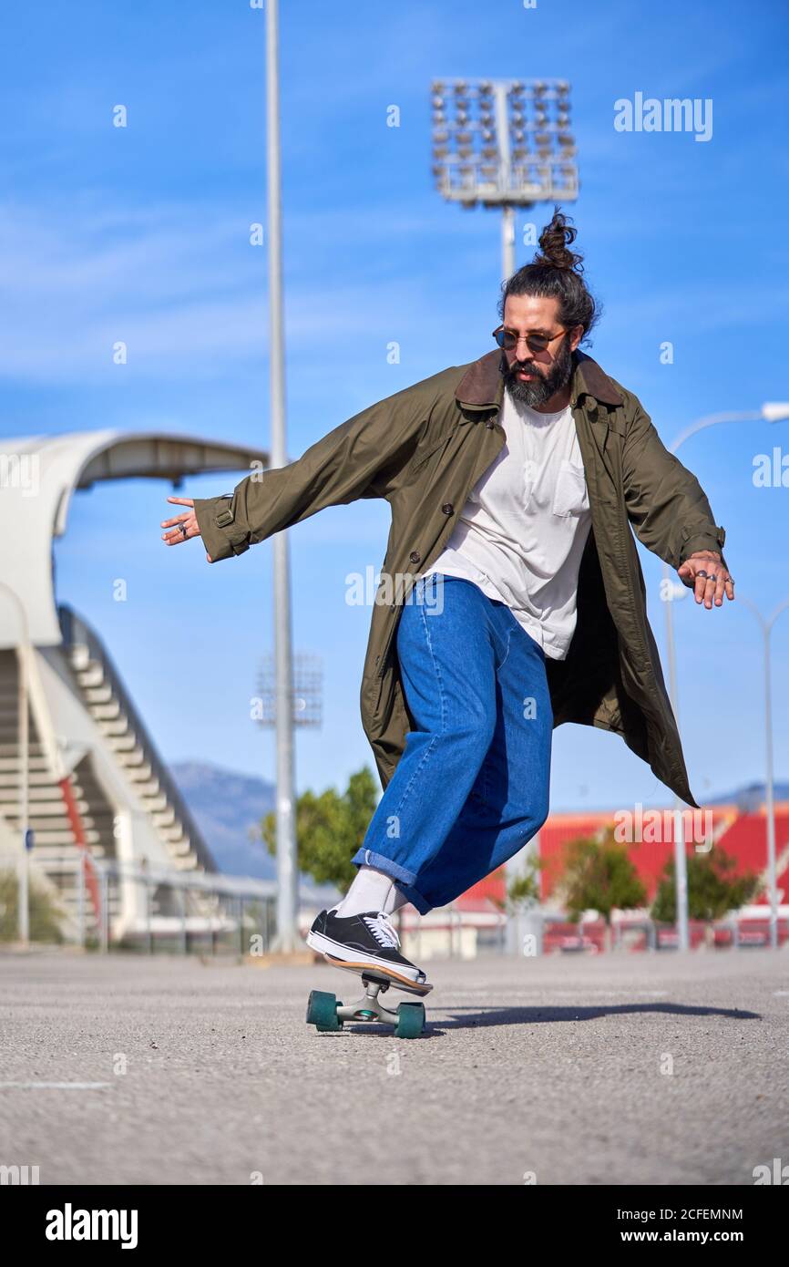 A Man skating on a skateboard on the road with his raincoat and sunglasses  Stock Photo - Alamy