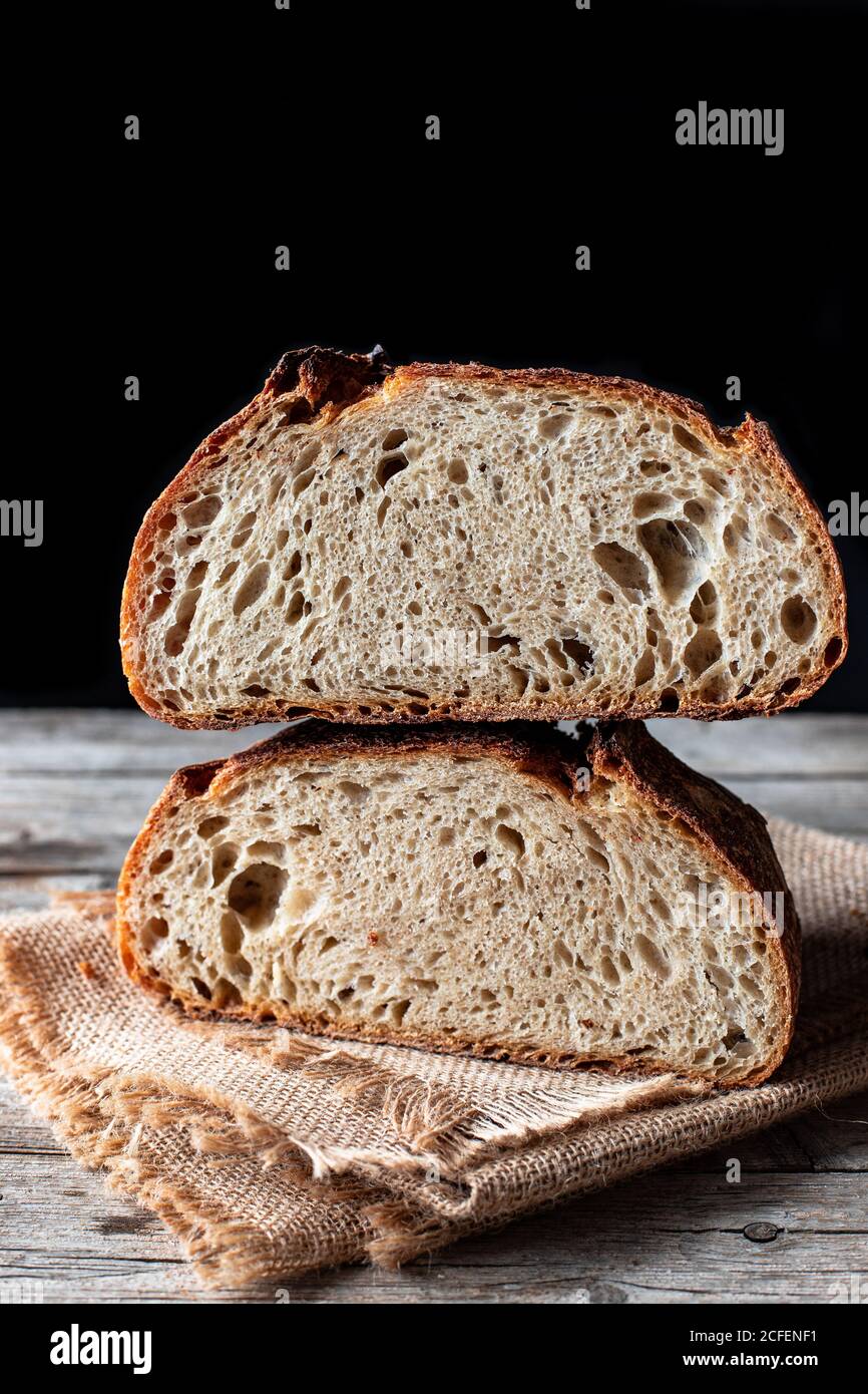 Pieces of tasty fresh bread falling on napkin on table against black background Stock Photo