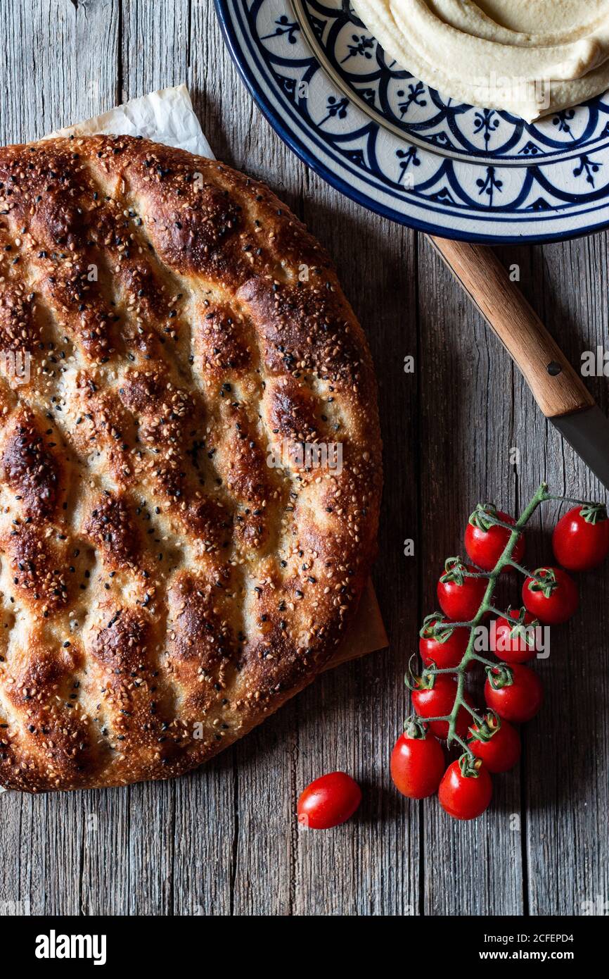 From above loaf of Ramazan pidesi placed near fresh tomatoes and spices on lumber tabletop Stock Photo