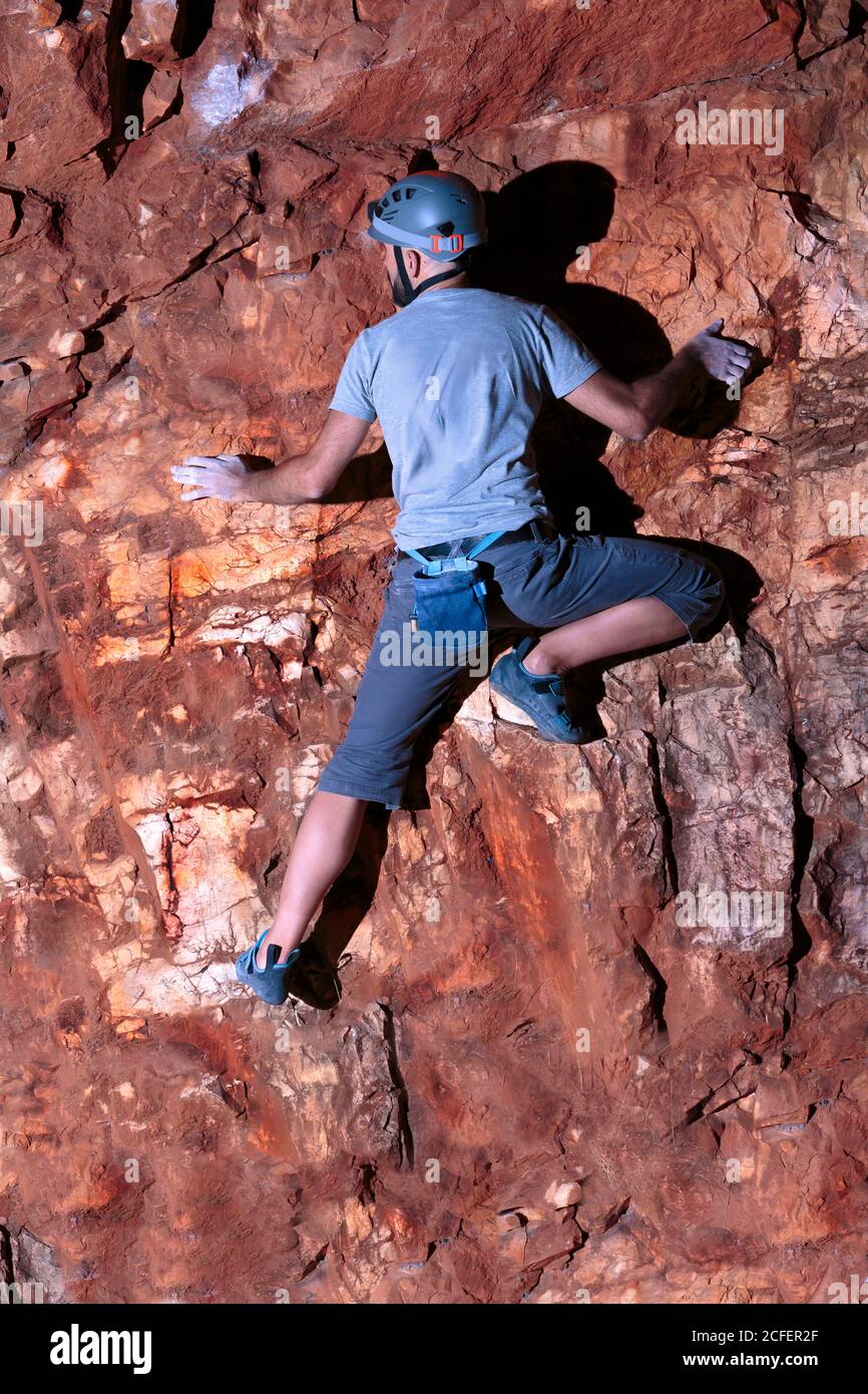 Courageous hispanic male climber carefully balanced on a rock wall Stock Photo