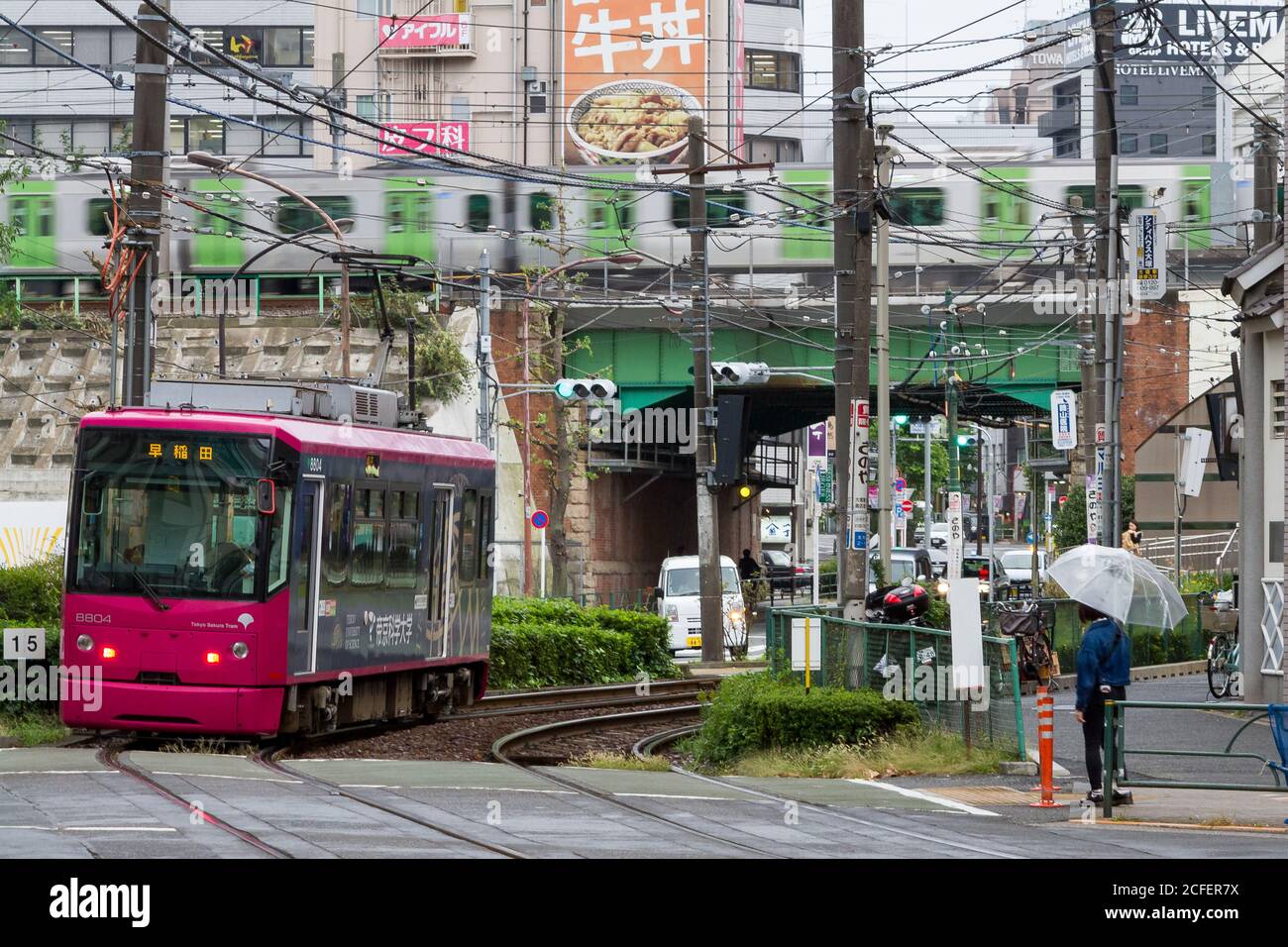A tram or streetcar on the Toden Arakawa Line in Otsuka with a Yamanote line train behind. Tokyo, Japan. Stock Photo