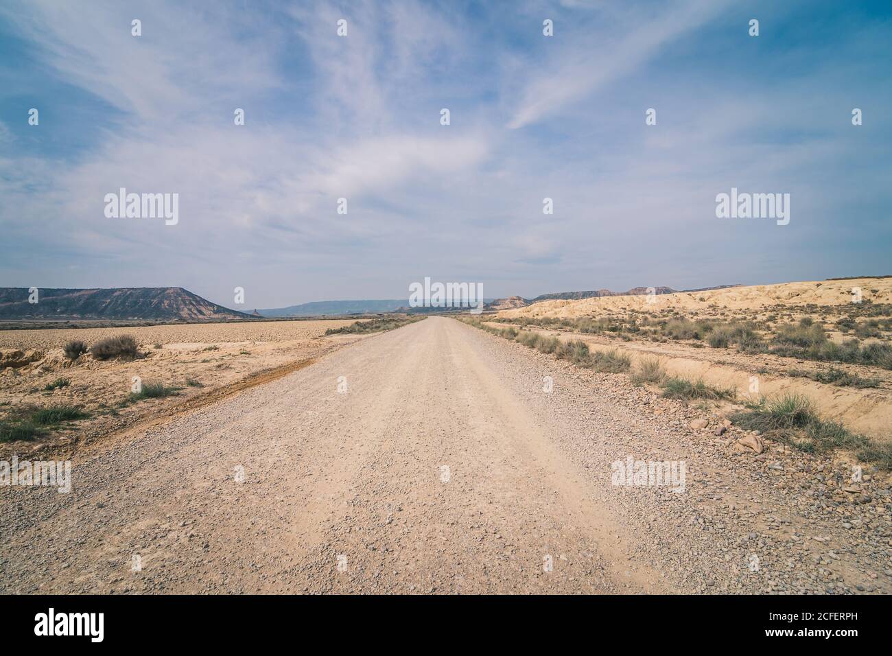 Desert dusty road stretchering high between abandoned dry area with vegetation in semi-desert Bardenas Reales Navarra Spain Stock Photo