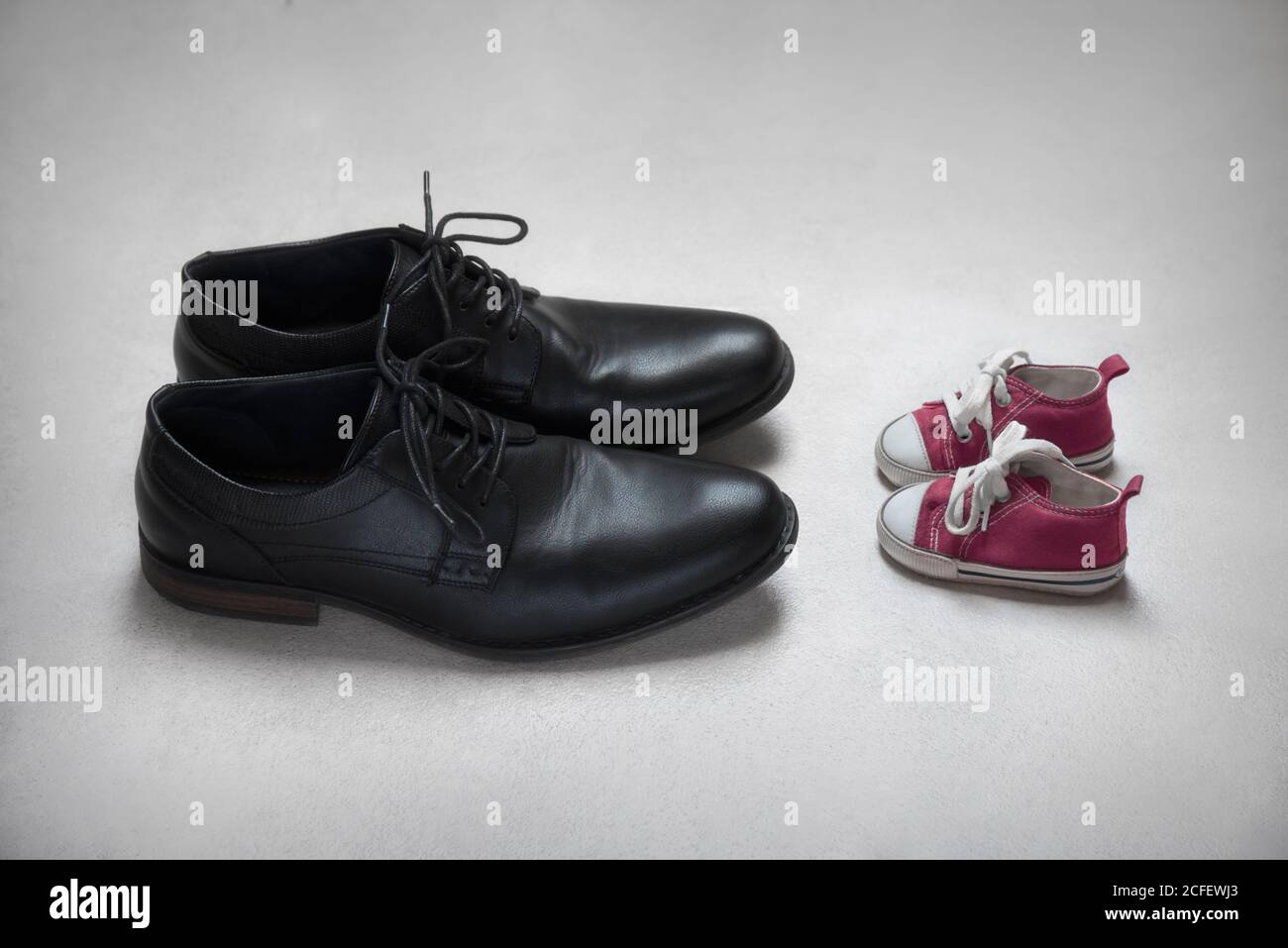 Father with daughter metaphor, baby and adult shoes. Stock Photo