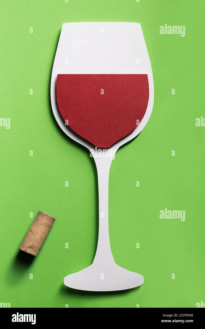 Silhouette of a glass of red wine made with cardboard on green background with a real cork Stock Photo