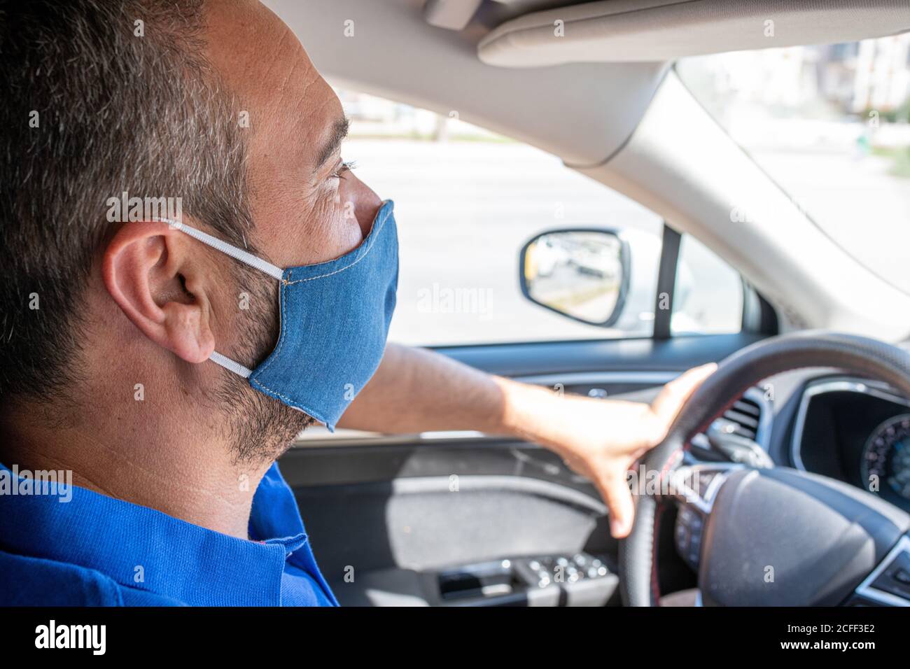 Man wearing protective mask to avoid the infection of virus and polluted air spreading deseases inside of his car. Health care, coronavirus, influenza Stock Photo