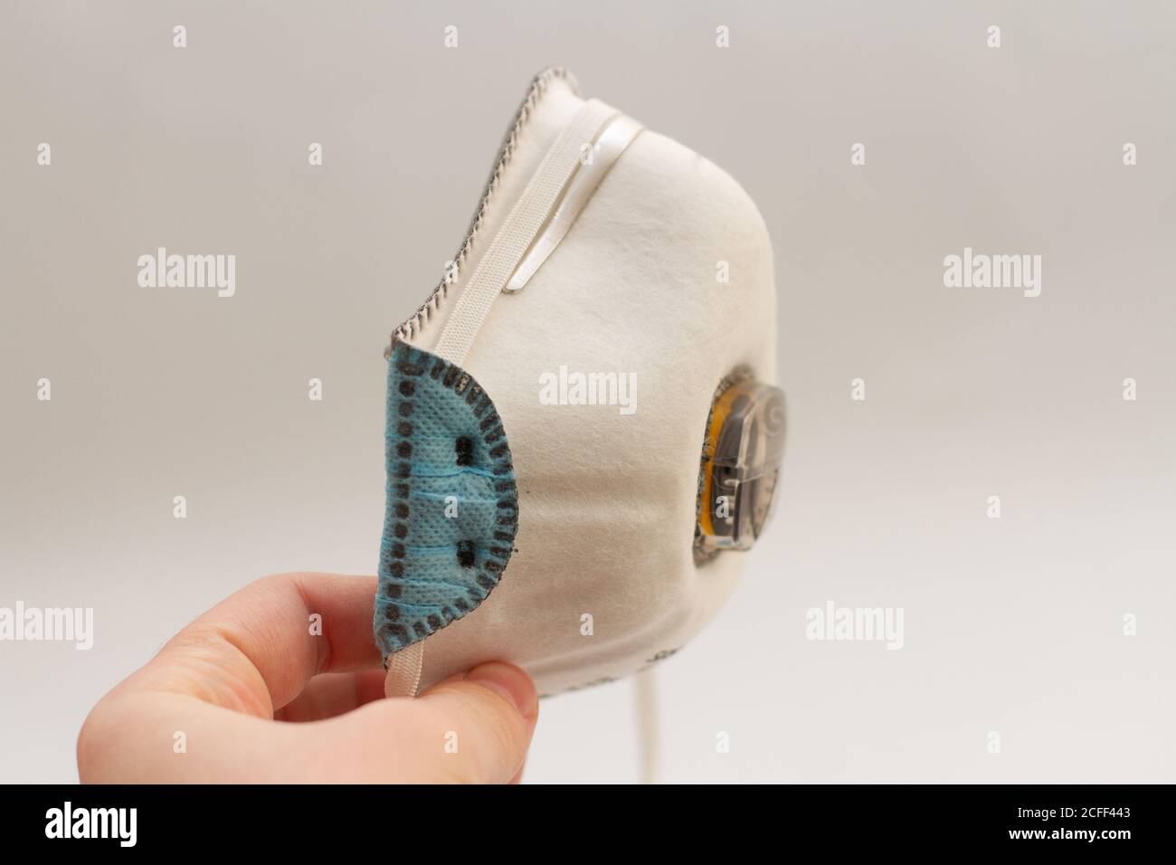 a mask respirator for face holds in hand on a white background Stock Photo