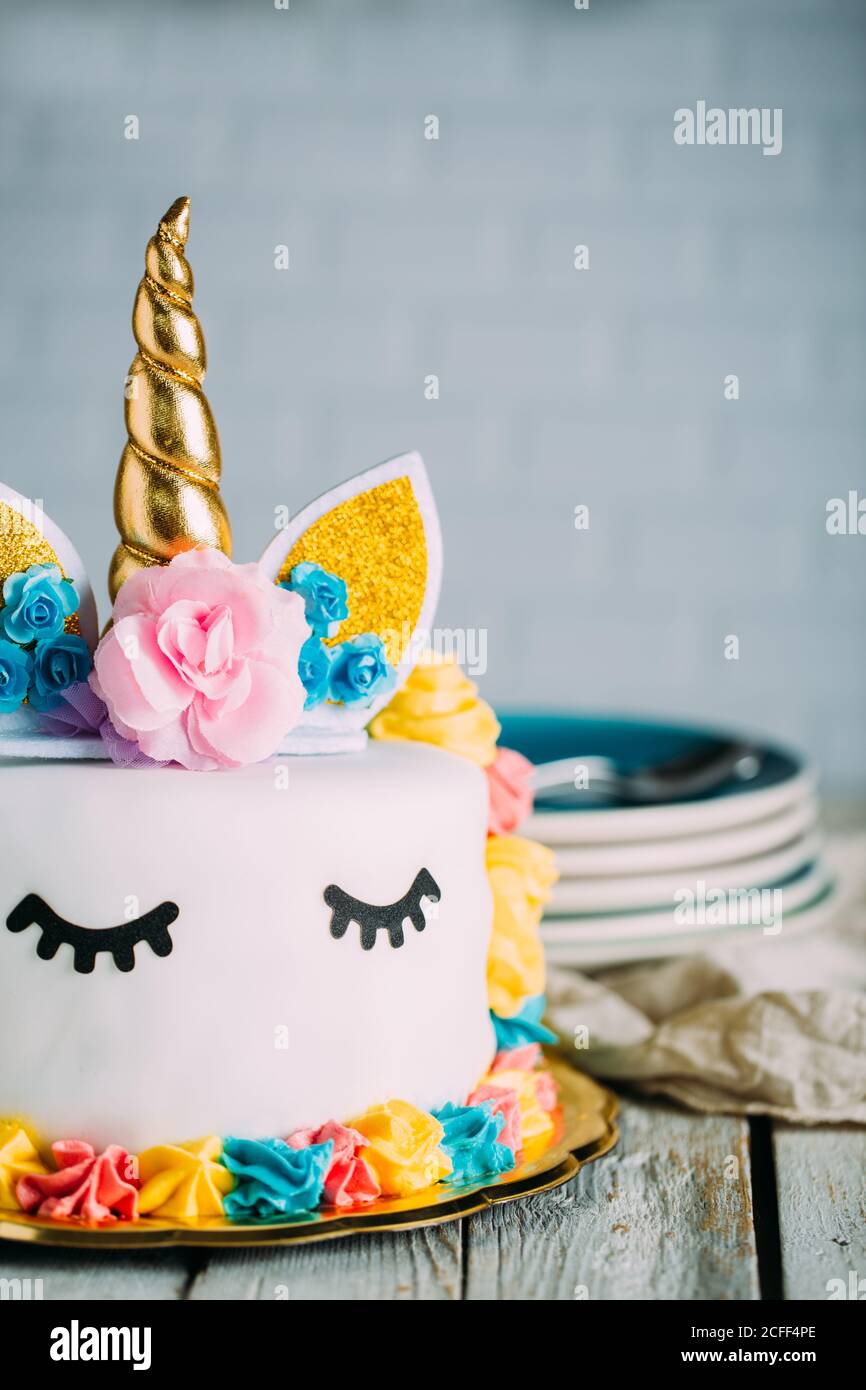 Tasty sweet festively decorated cake with sleeping unicorn on wooden table Stock Photo