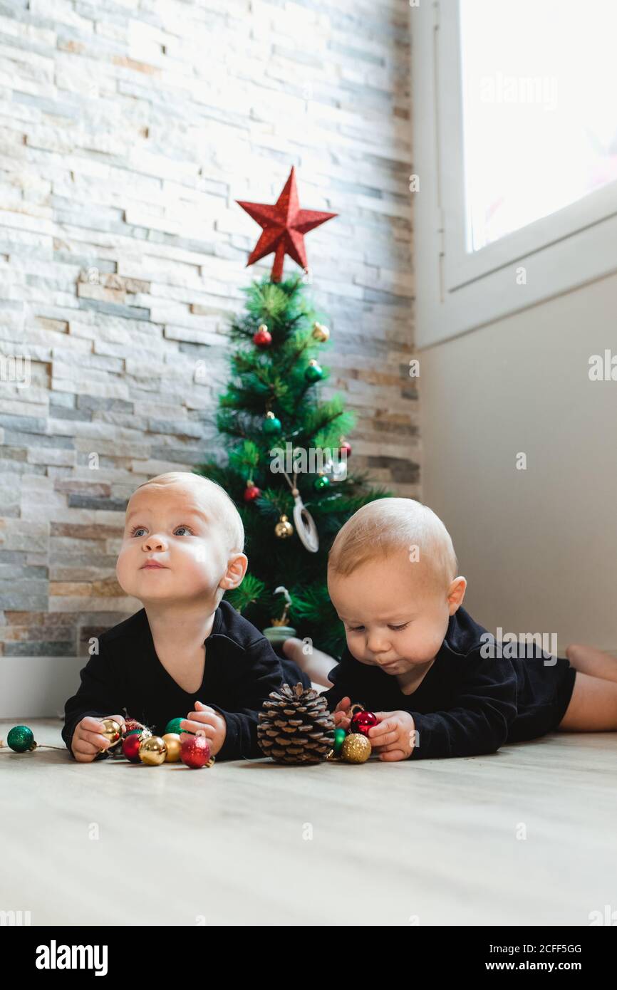 Twins on floor near Christmas tree Stock Photo