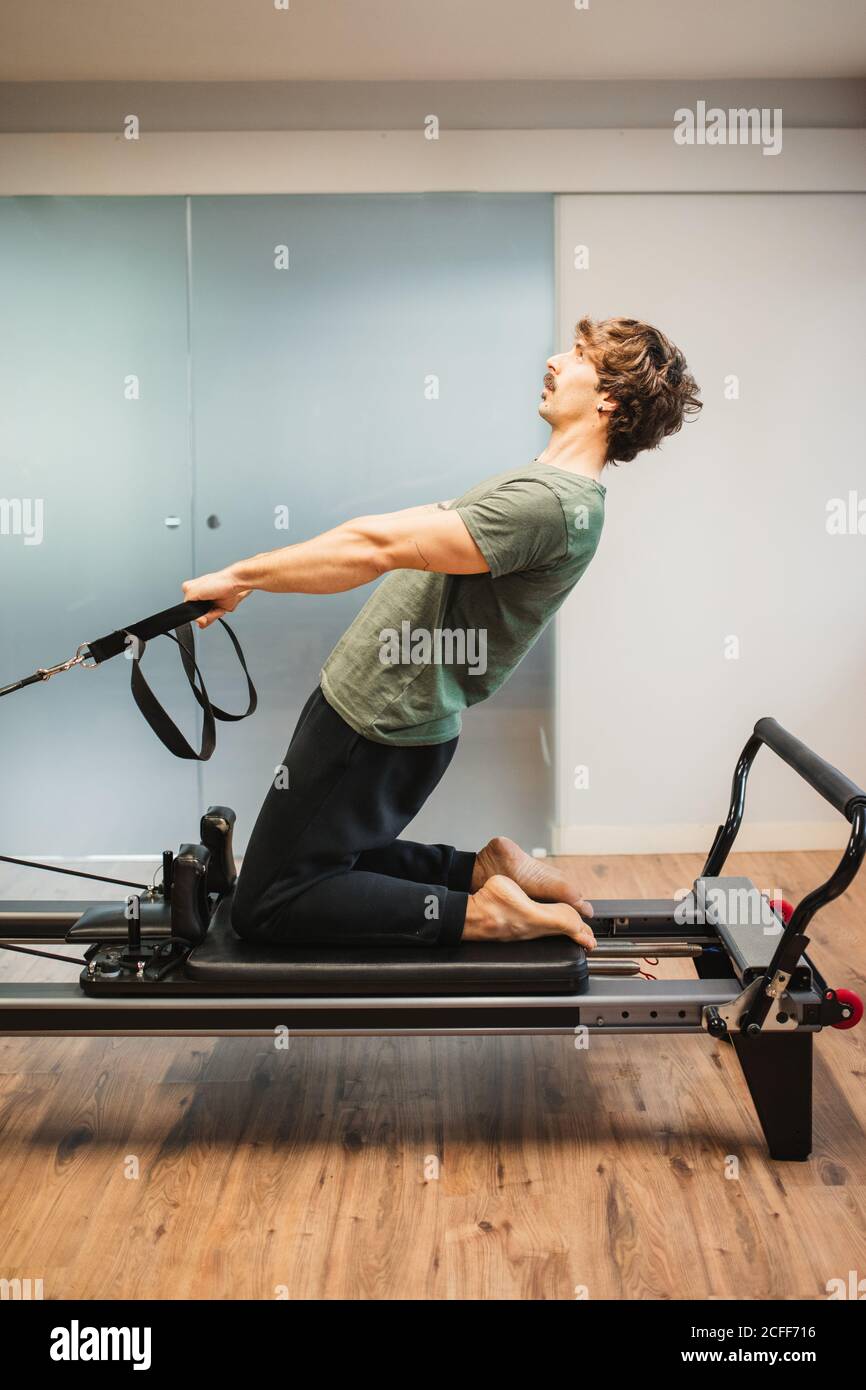 Side view of sportsman in activewear using pilates machine and stretching arms with resistance bands Stock Photo Alamy