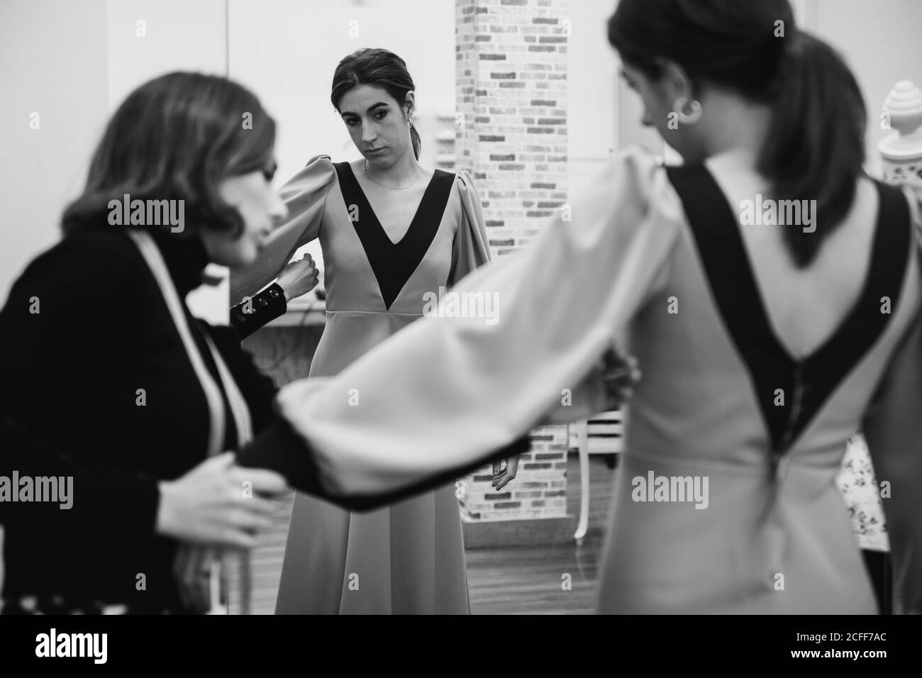 Dressmaker fitting custom gown on back of female client while working