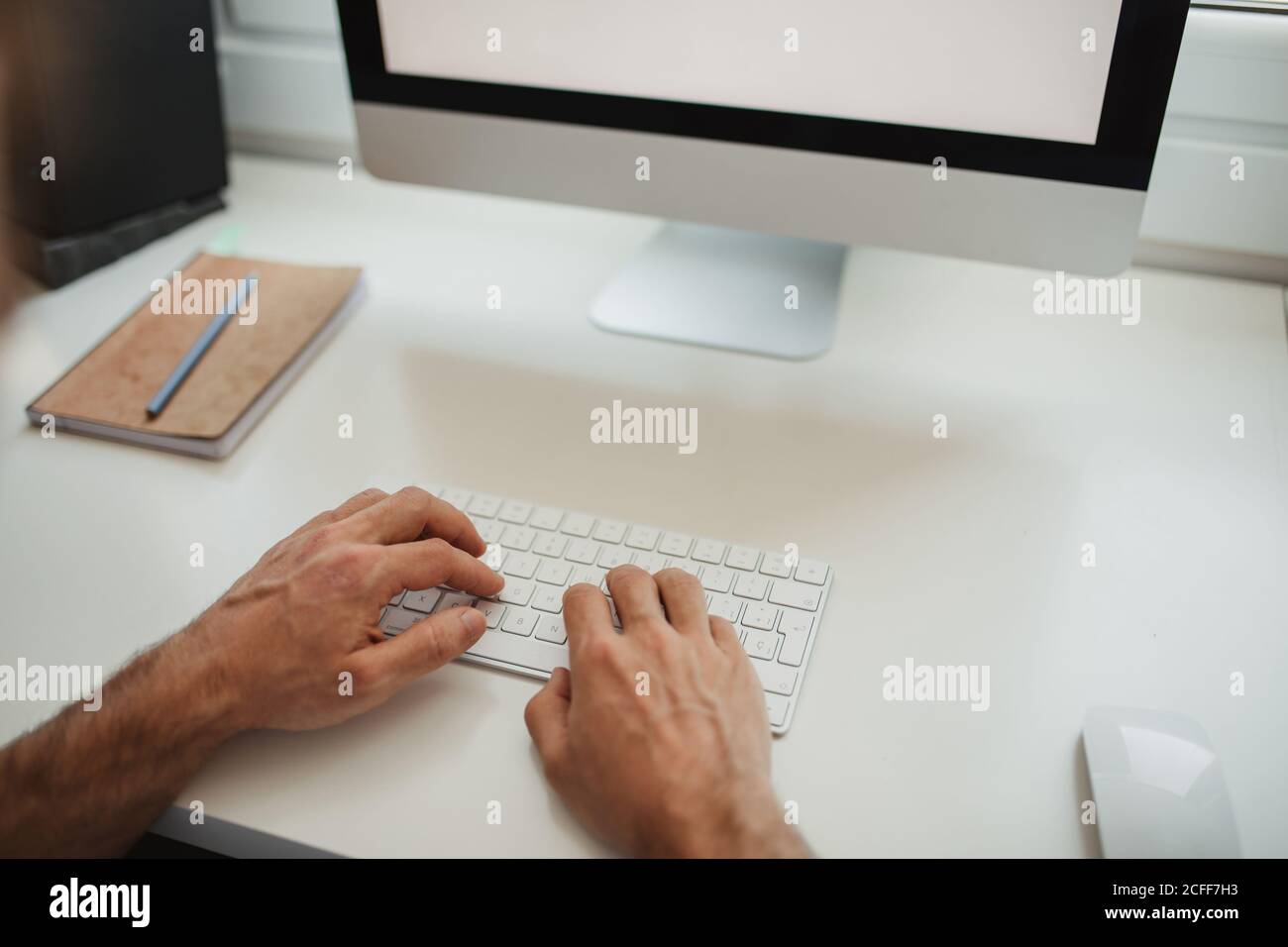Cropped unrecognizable male freelancer at table in creative workspace and typing on keyboard while working on online project Stock Photo