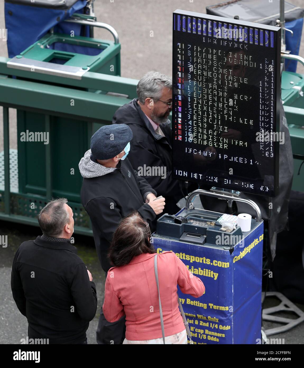 Racegoers look at the odds on a tote board during Betfair Sprint Cup Day 2020 at Haydock Racecourse, Newton-le-Willows. Stock Photo