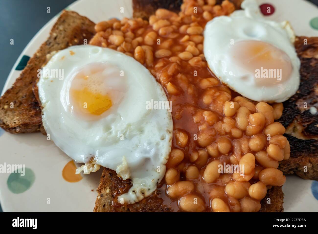 2 Fried eggs with baked beans on brown bread toast snack Stock Photo