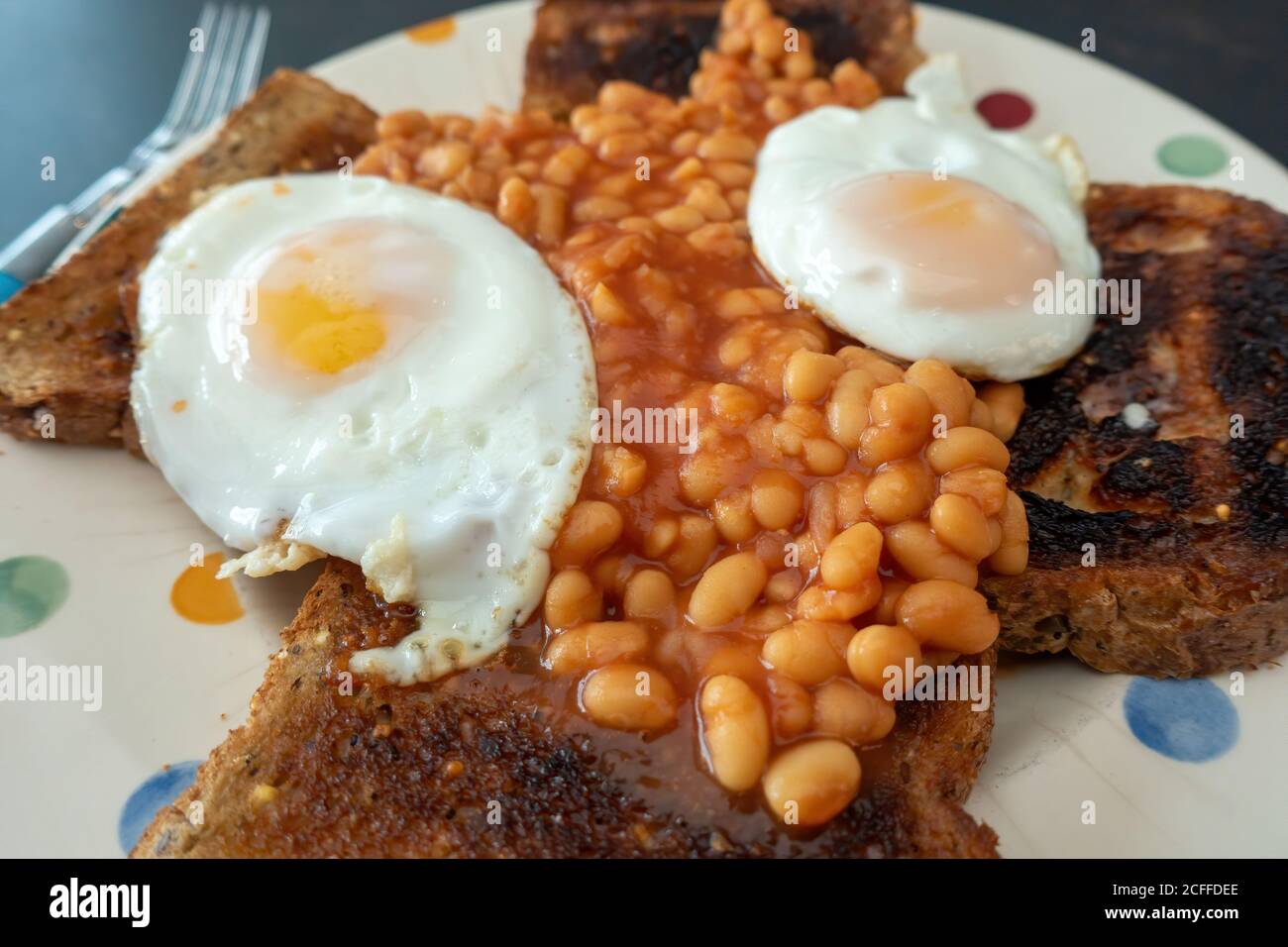 2 Fried eggs with baked beans on brown bread toast snack Stock Photo