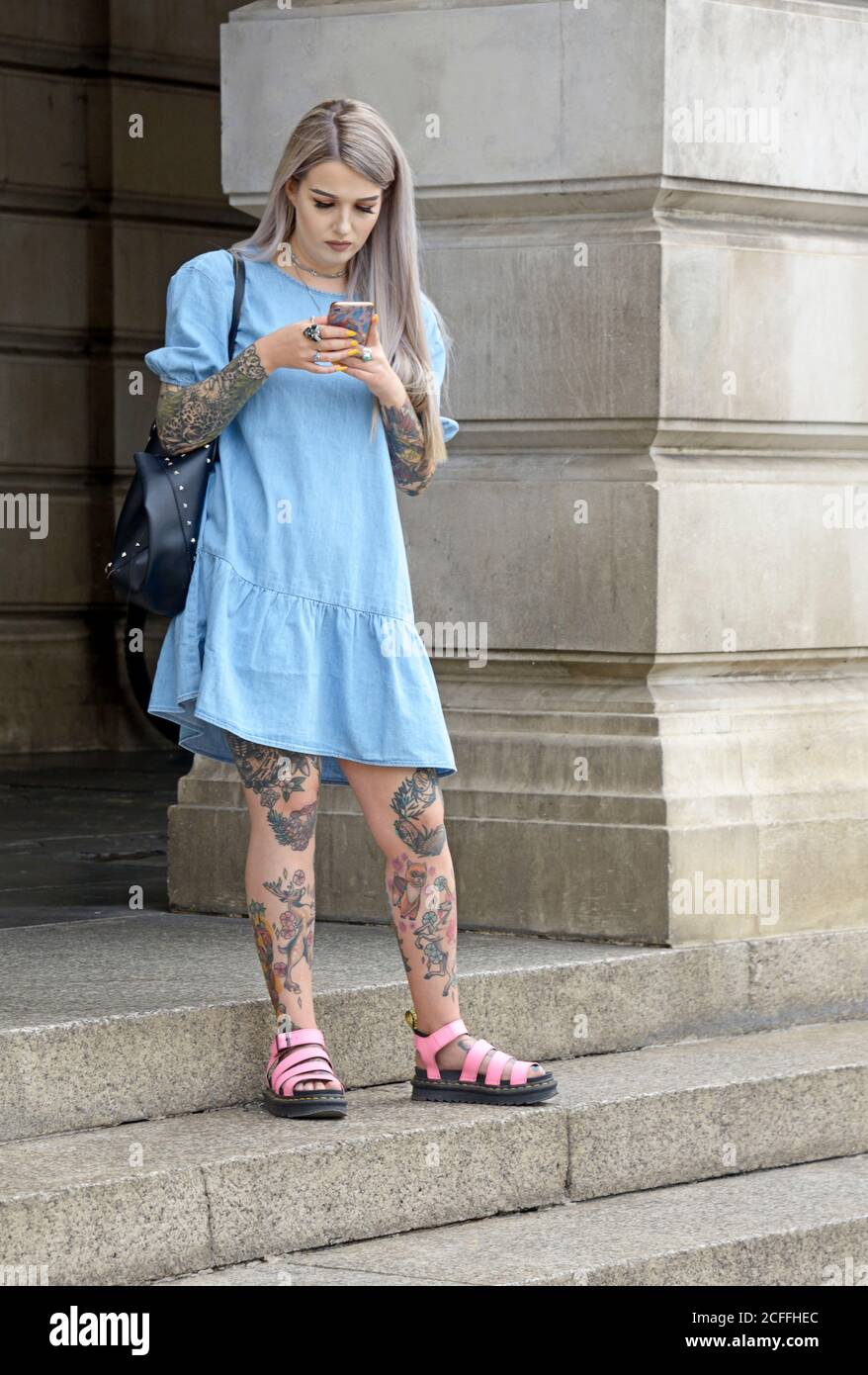 Young woman with tattooed limbs, in blue dress Stock Photo
