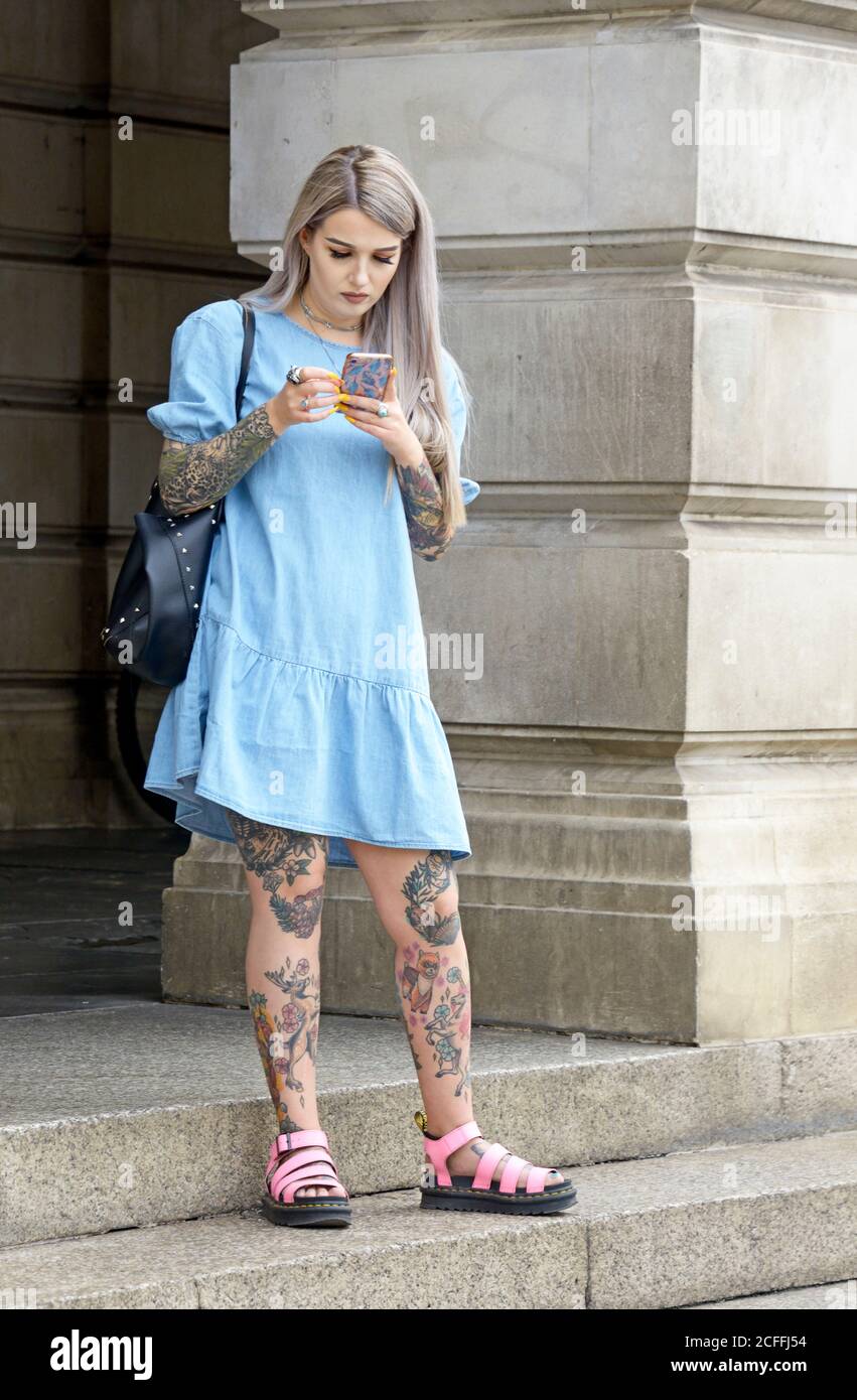 Young woman with tattooed limbs, in blue dress Stock Photo