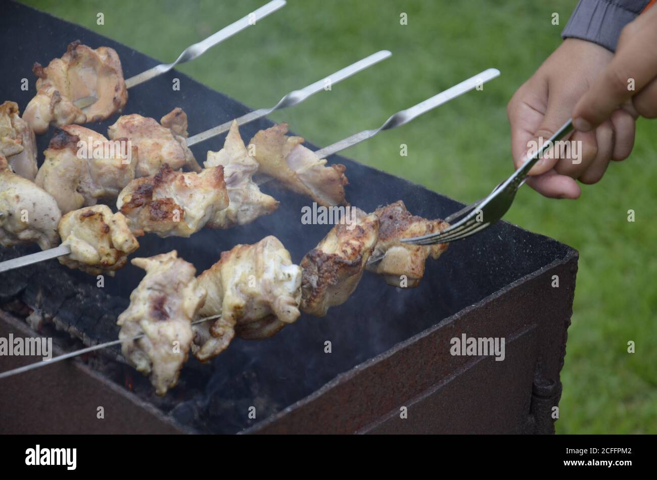 Cooking chicken skewers. In a hand fork and a skewer.  Stock Photo