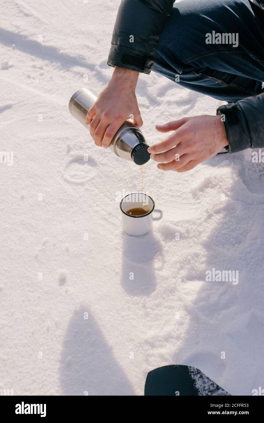 https://c8.alamy.com/comp/2CFFR53/crop-male-traveler-pouring-hot-tea-from-thermos-bottle-to-enamel-mug-placed-on-snow-during-winter-trip-in-siberia-russia-2CFFR53.jpg