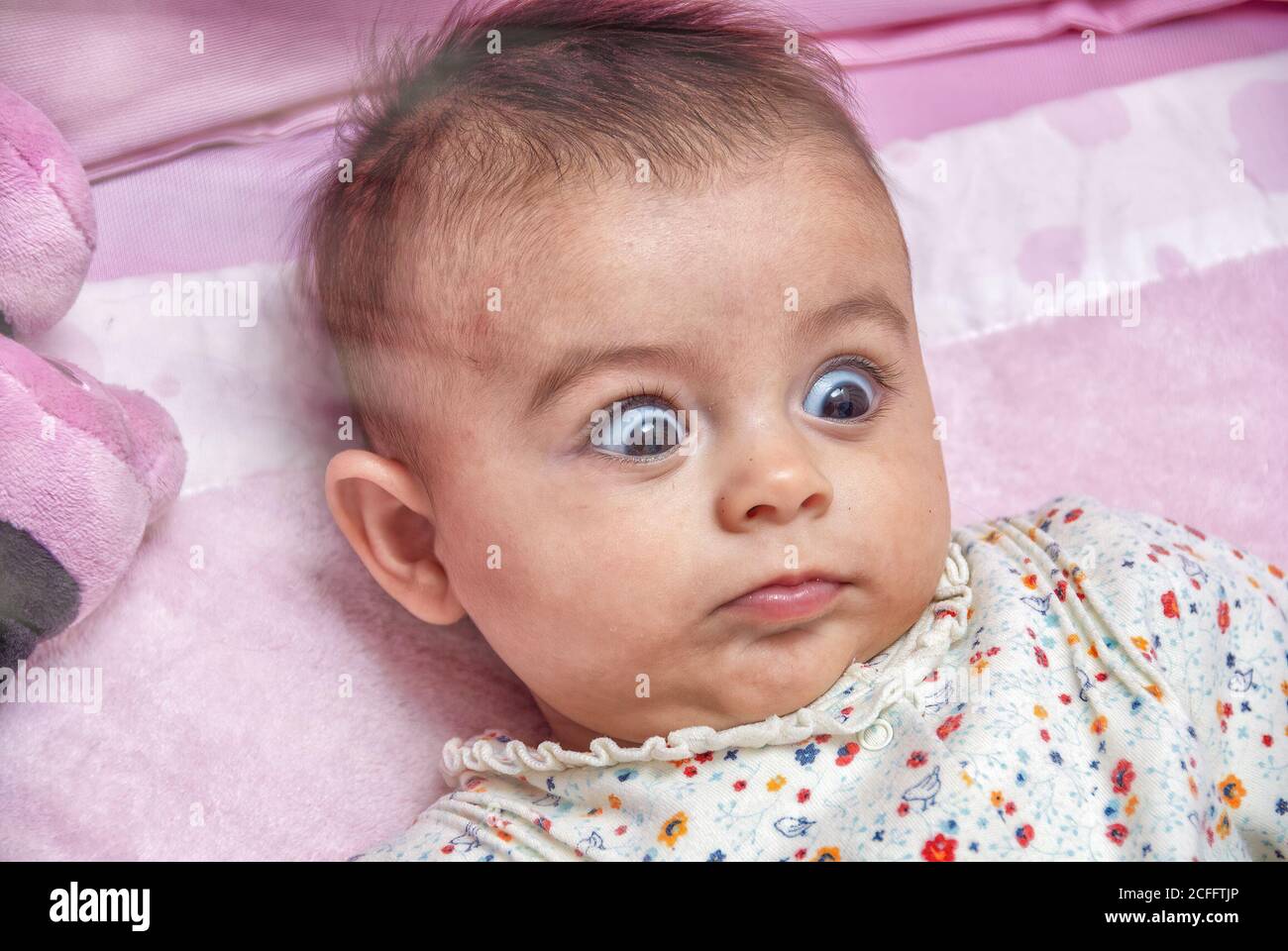 Interrogative and surprised expression of a young baby in the cradle ...