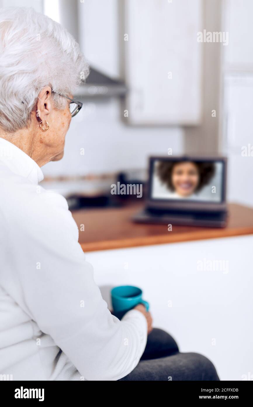 Senior Woman drinking tea and talking with daughter on laptop Stock Photo