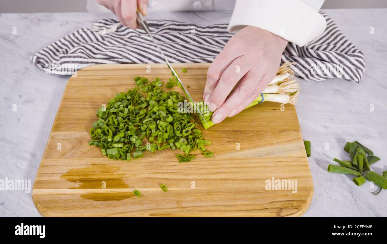 Step by step. Chopping organic green onions on a wood cutting board ...