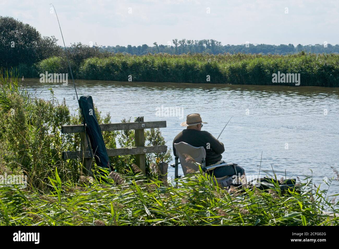 Coarse fishing on the Norfolk Broads Man sitting relaxed on reed bank