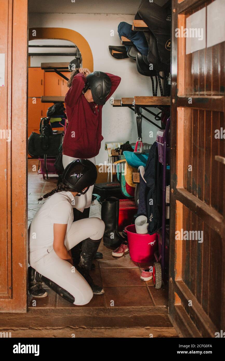 Side view of women in closet with staff getting dressed for horse riding Stock Photo